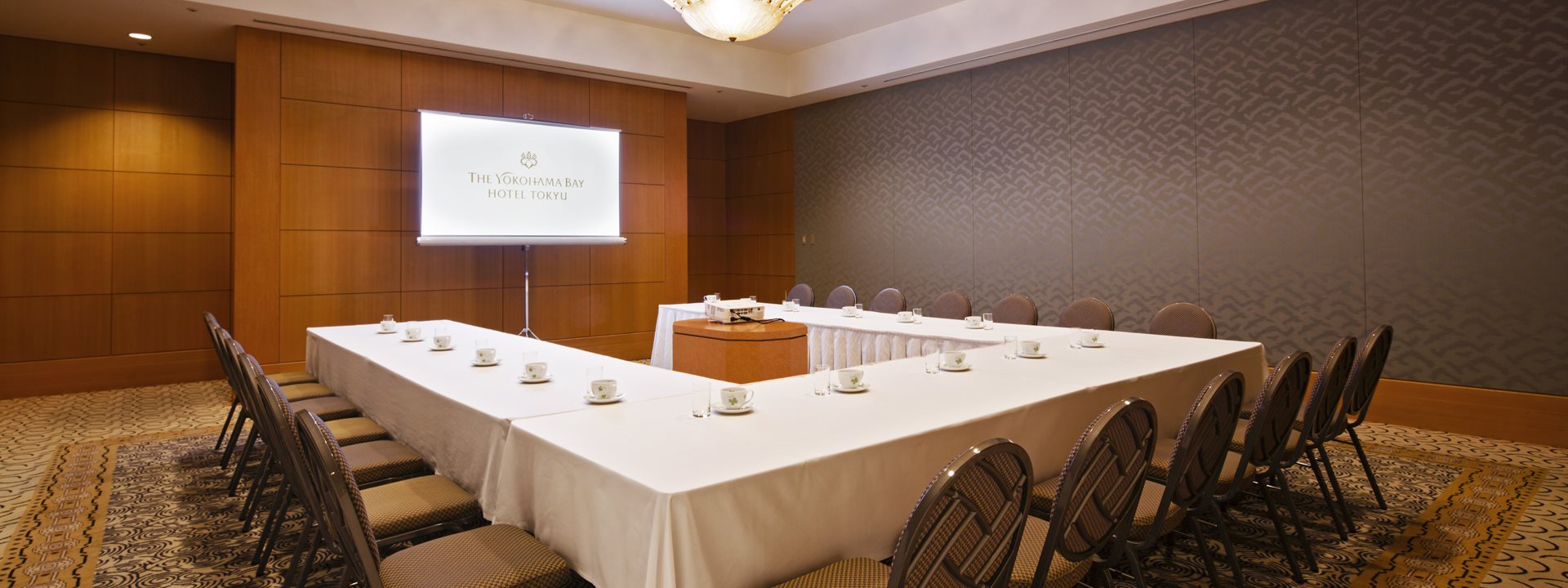 The "Princess" banquet hall at the Yokohama Bay Hotel Tokyu. A monitor is installed at the front, and the tables and chairs are arranged in a U-shape. Photo taken from an oblique angle.